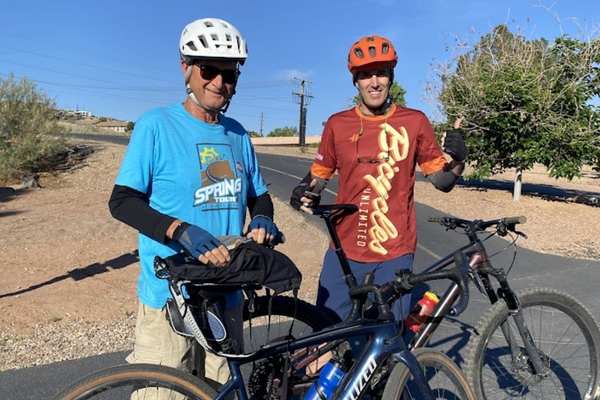 Two adults wearing helmets standing with bicycles outdoors at the Bike to Work Event.