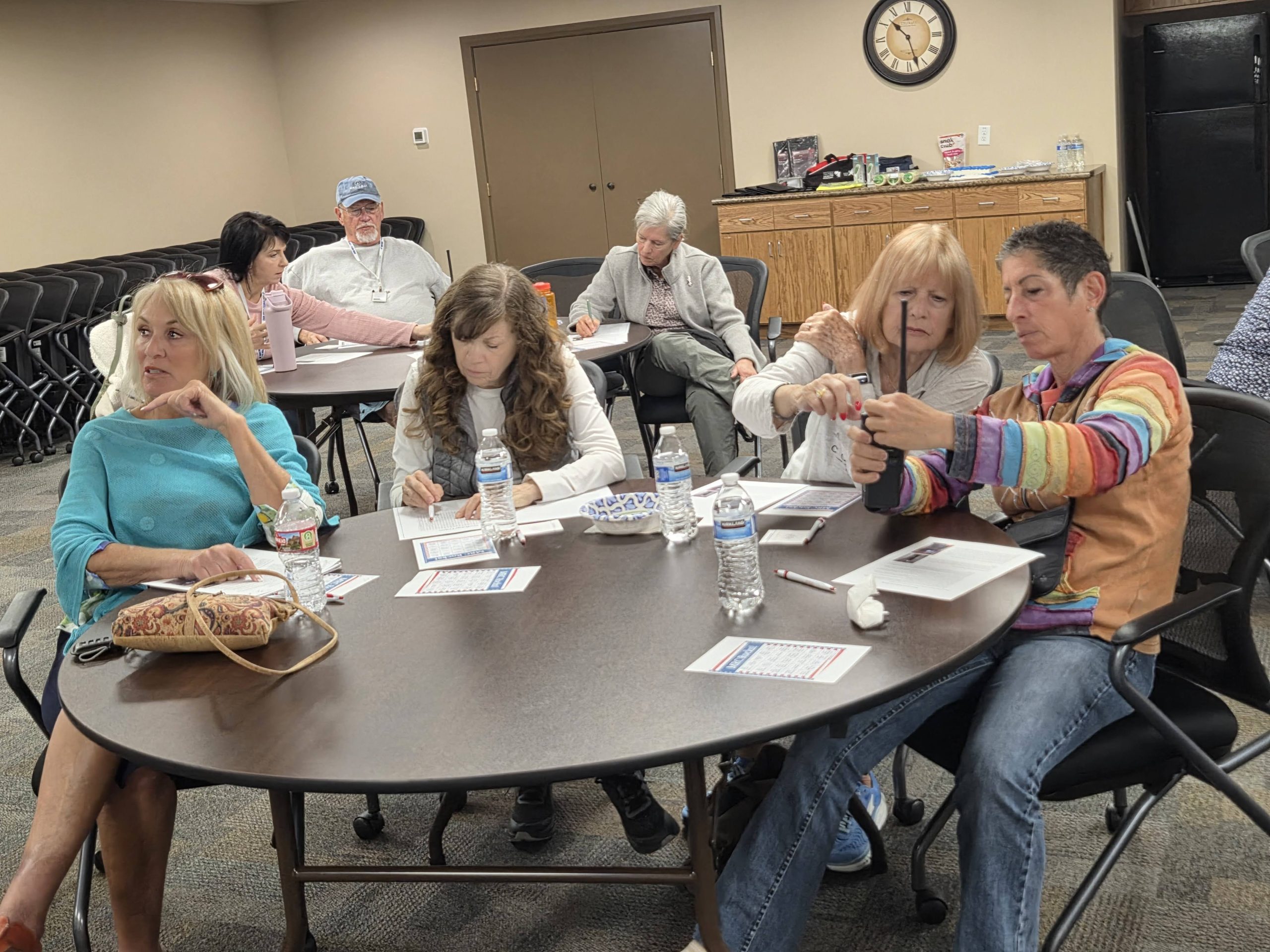Volunteers seated at a table in a classroom setting, learning and completing activities during a training session.