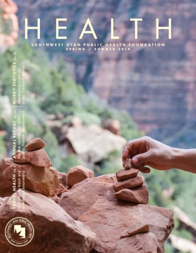 Front cover of "HEALTH" magazine, Spring/Summer 2014 issue, featuring a photograph of a hand carefully stacking and balancing small red rocks to build a stone cairn.