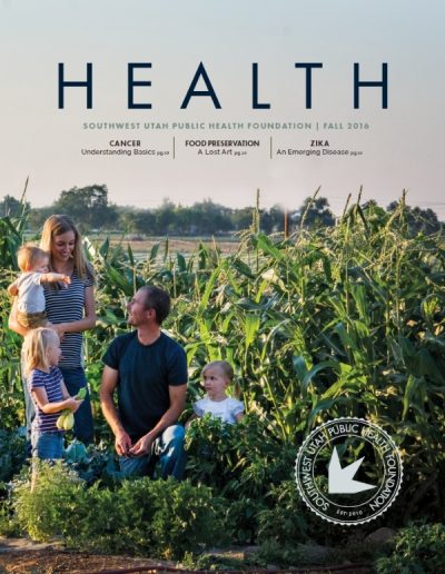Front cover of "HEALTH" magazine by the Southwest Utah Public Health Foundation, Fall 2016 issue. The photograph shows a smiling family of five—a mother holding a toddler, a father kneeling, and two young children—together in a lush garden filled with cornstalks and leafy green plants.