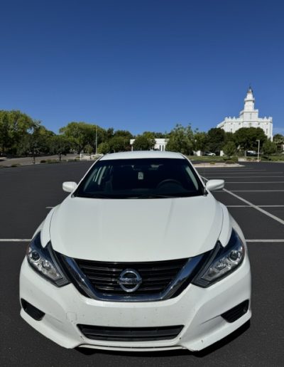 Front view of a white 2018 Nissan Altima showing the front grille, headlights, and hood.